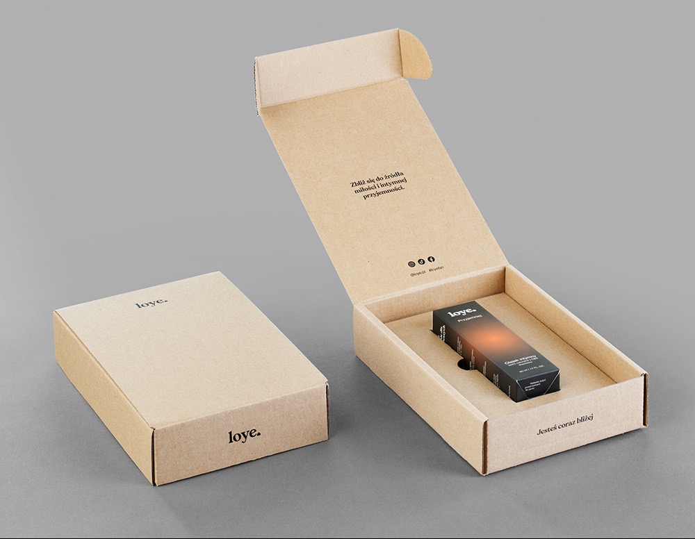 Beżowe pudełka z tektury falistej z napisem 'loye.', jedno zamknięte, drugie otwarte z produktem w środku. Minimalistyczny design, neutralne tło.