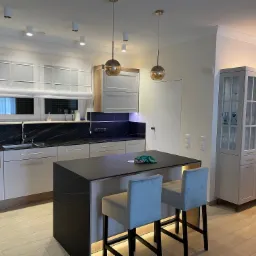 Nowoczesna kuchnia z wyspą i oświetleniem LED pod blatem wyspy oraz przeszkloną witryną w kolorze szarym.