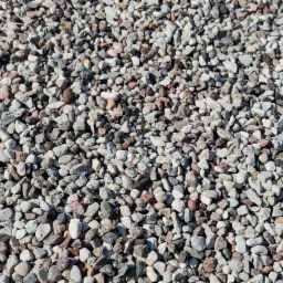 Drobny żwir o nieregularnych kształtach i zróżnicowanej kolorystyce: szary, biały, różowy i brązowy, tworzący jednolitą warstwę.