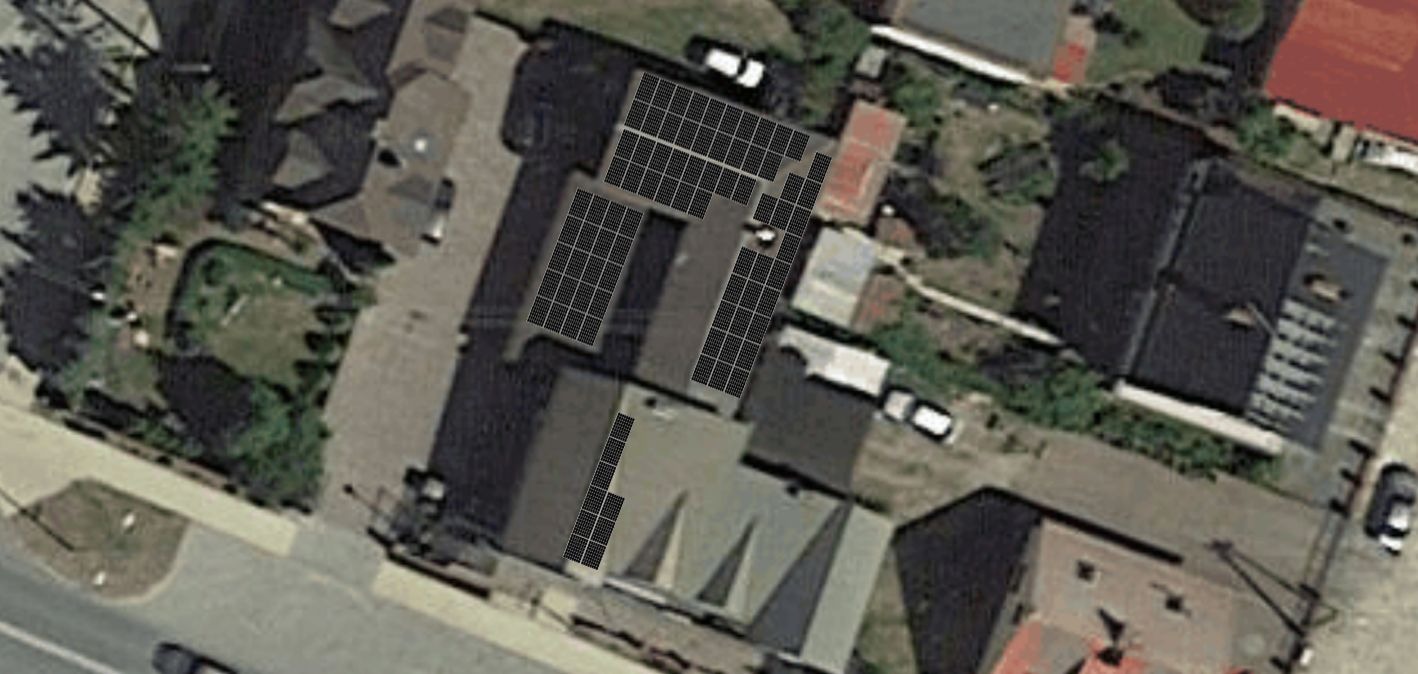 Widok z lotu ptaka na budynki z panelami słonecznymi na dachach, otoczone zielenią i samochodami.