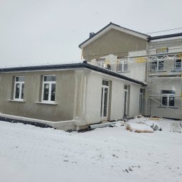 DYSTRYBUCJA 88 Sp. z o.o. - Budynek w trakcie tynkowania elewacji w zimowej scenerii, widoczne rusztowania, ocieplenie i lekki sprzęt budowlany w tle.