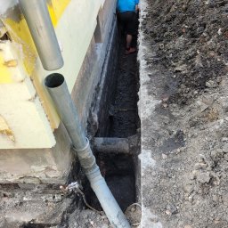 DYSTRYBUCJA 88 Sp. z o.o. - Odkopane fundamenty budynku z widoczną izolacją termiczną, rurami odprowadzającymi wodę i pracownikiem w wykopie.