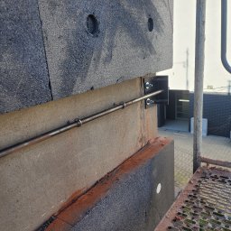 DYSTRYBUCJA 88 Sp. z o.o. - Montaż ocieplenia elewacji z widocznymi elementami mocującymi i fragmentem rusztowania.