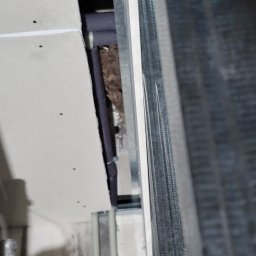 DYSTRYBUCJA 88 Sp. z o.o. - Konstrukcja metalowa pod płytę gipsową z widoczną izolacją w przestrzeni między ścianą a płytą, pionowy kadr.