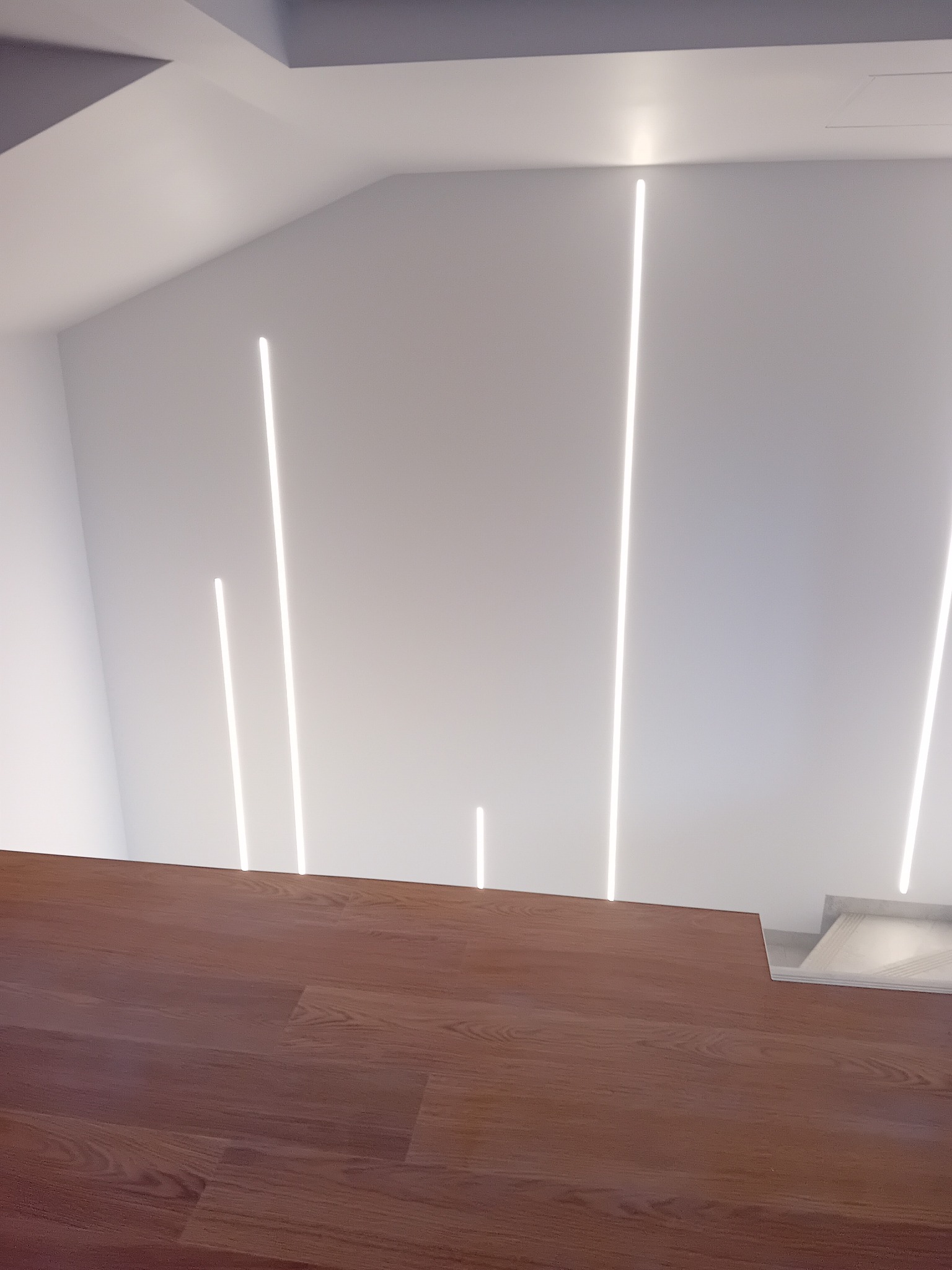 Minimalistyczne wnętrze: parkiet w kolorze drewna i białe ściany z pionowymi liniami świetlnymi LED.