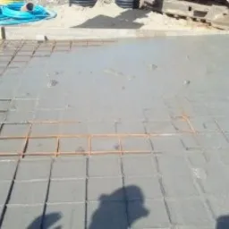 Zalewanie betonem zbrojenia fundamentów w Ostrówku, widoczny fragment koparki w tle.