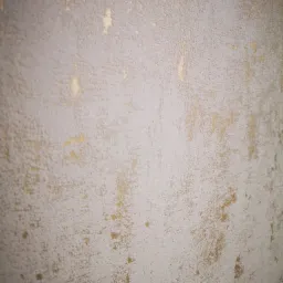 Tekstura ściany pomalowanej na szaro z widocznymi przetarciami i fragmentami złotej farby, tworzącymi efekt dekoracyjny.