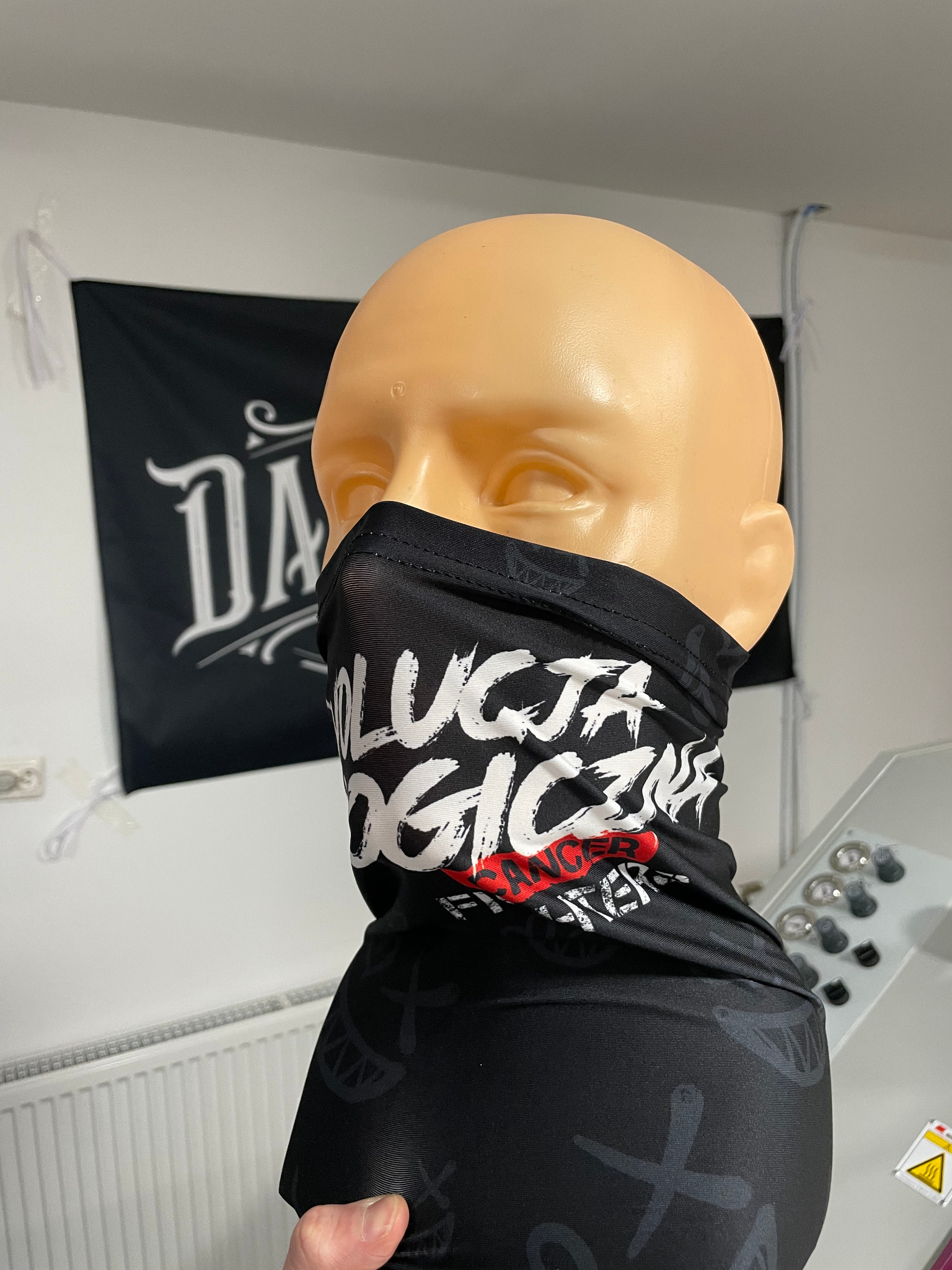Czarna, elastyczna chusta z nadrukiem 'Rewolucja Logiczna' na manekinie, z widocznym tłem z flagą.