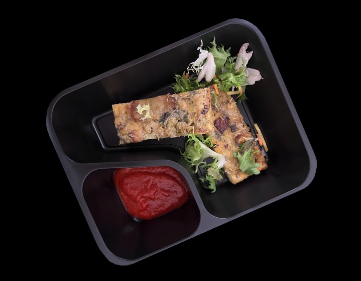 Gotowe danie w czarnym, nowoczesnym pojemniku z przegródkami, zawierające porcję zapiekanki z warzywami i mięsem, świeżą sałatkę oraz sos pomidorowy, całość ułożona w kształt pistoletu.