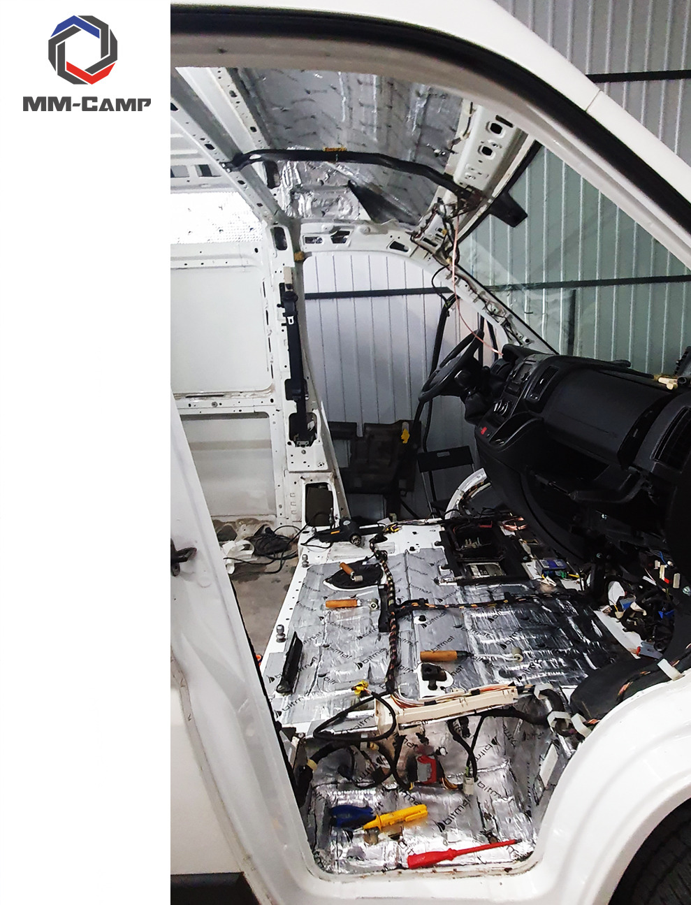 Wnętrze furgonetki w trakcie wygłuszania, widoczne materiały izolacyjne na podłodze i ścianach, narzędzia pracy, częściowo zdemontowana deska rozdzielcza.