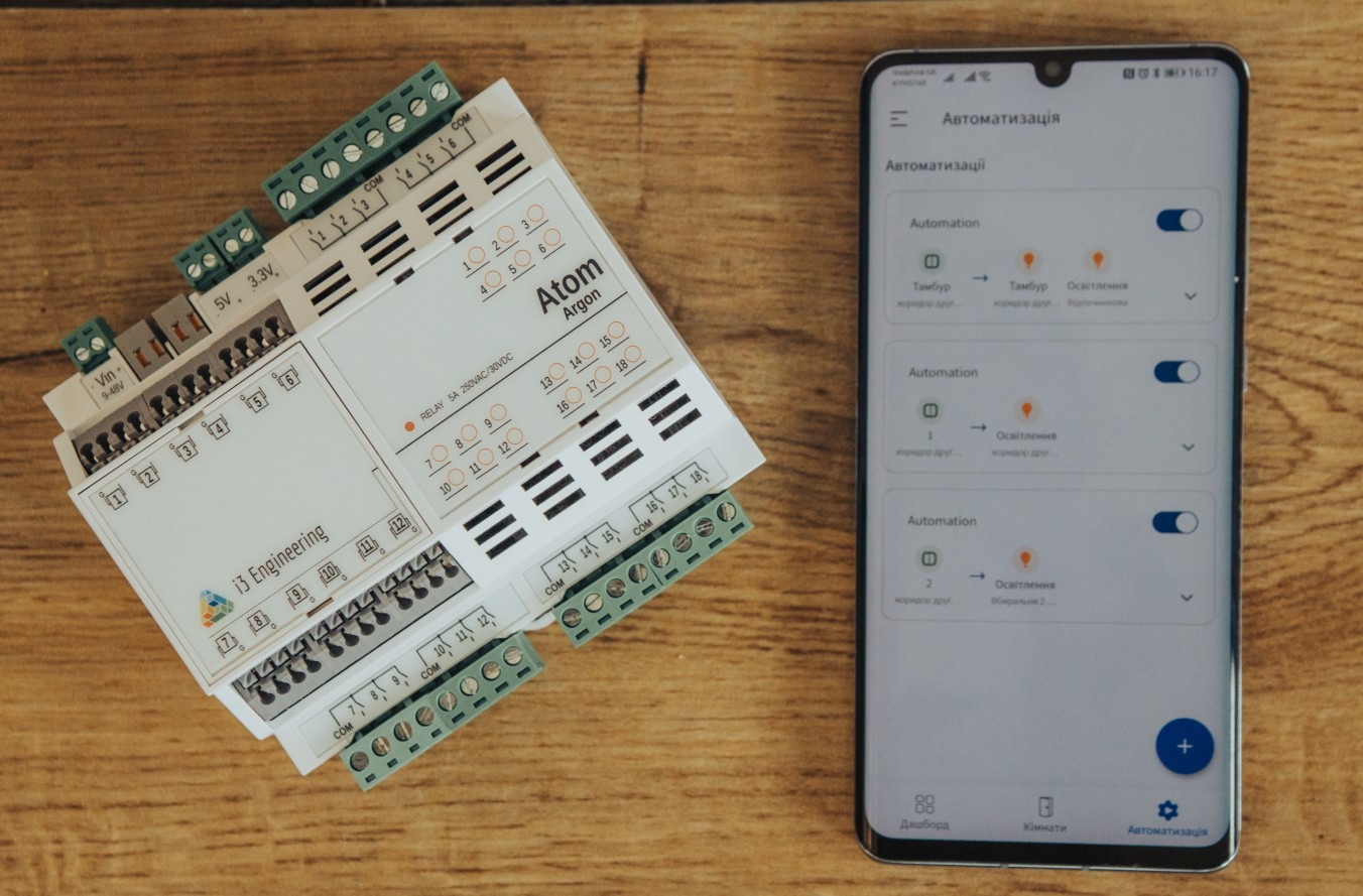Kontroler inteligentnego domu Atom Argon i aplikacja mobilna do zarządzania automatyzacjami oświetlenia na drewnianym biurku.