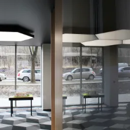 Wnętrze biura z geometryczną podłogą 3D, model architektoniczny budynku na czarnym stoliku, widok na ulicę przez duże okna.