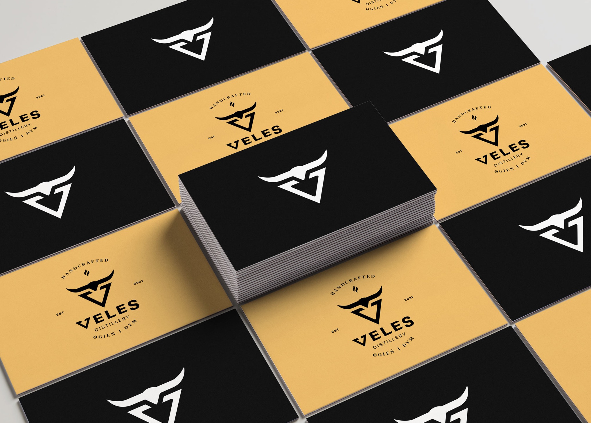 Stos wizytówek w kolorach czerni i złota z logo stylizowanym na głowę byka w trójkącie, ułożonych na przemian na białym tle.