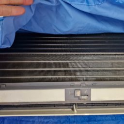 Klima Partner - Czyszczenie klimatyzatora w domu z użyciem niebieskiego pokrowca ochronnego na elementy elektroniczne.