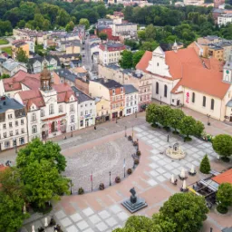 Panorama Rynku w Chojnicach z lotu ptaka, widoczny kościół, ratusz i zabytkowa zabudowa, w rogu logo firmy Tutum House.