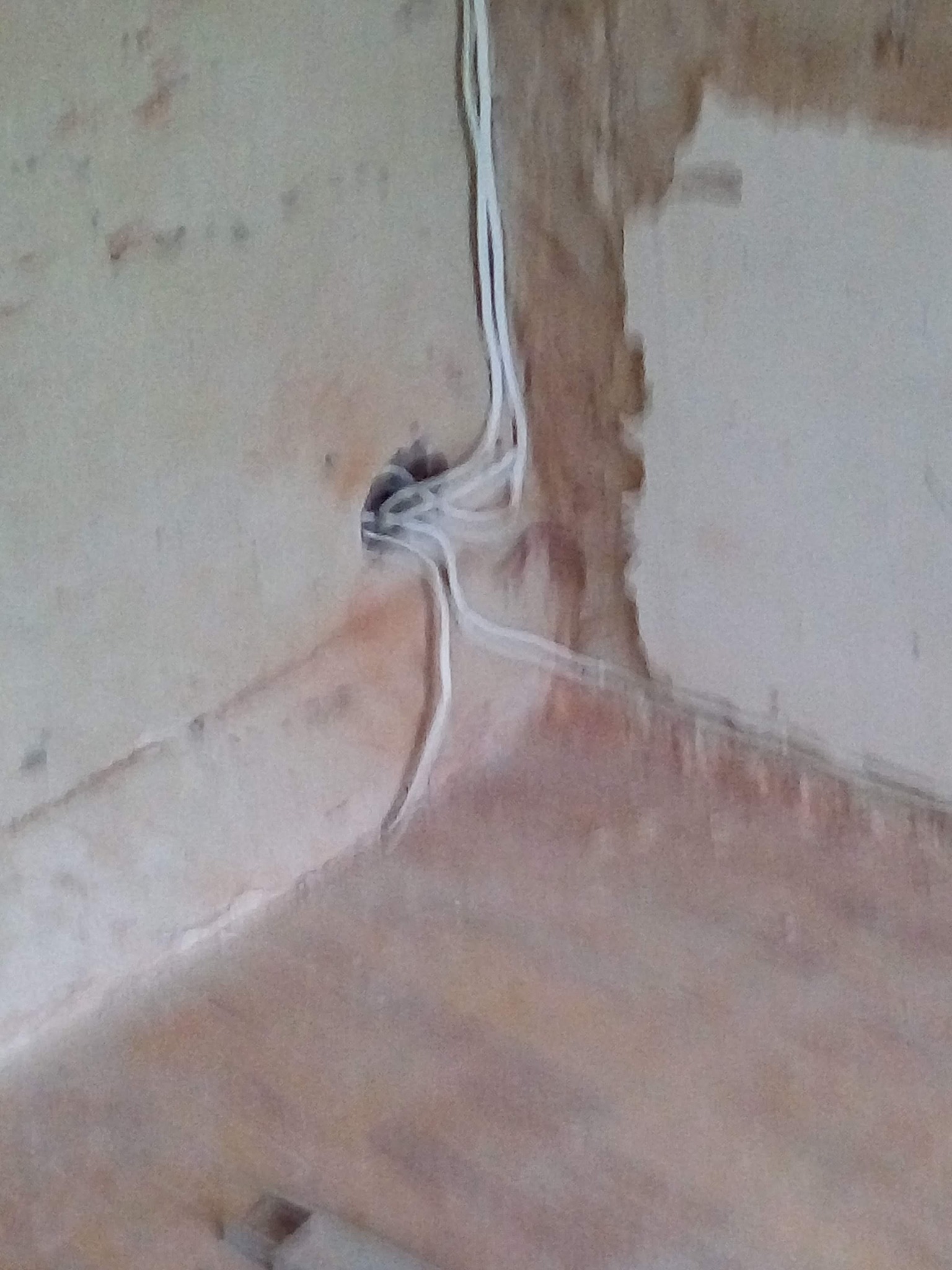 Otwór w ścianie z wystającymi przewodami elektrycznymi, ściana w stanie surowym przed wykończeniem.