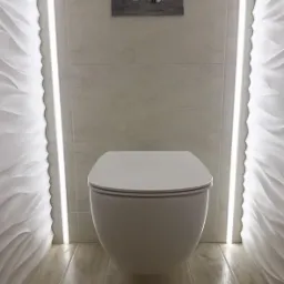 Wisząca toaleta z zabudowanym systemem spłukiwania, podświetlona dekoracyjnymi listwami LED i ozdobnymi panelami ściennymi.