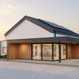 ATO-ARCHITEKTURA - Wizualizacja domu jednorodzinnego z panelami słonecznymi na dachu, drewnianą elewacją i dużymi oknami, przez które widać wnętrze. W tle para z psem.