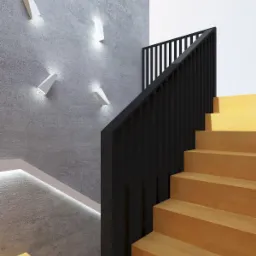 Schody drewniane z czarną balustradą na tle betonowej ściany z designerskimi, białymi lampami ściennymi.