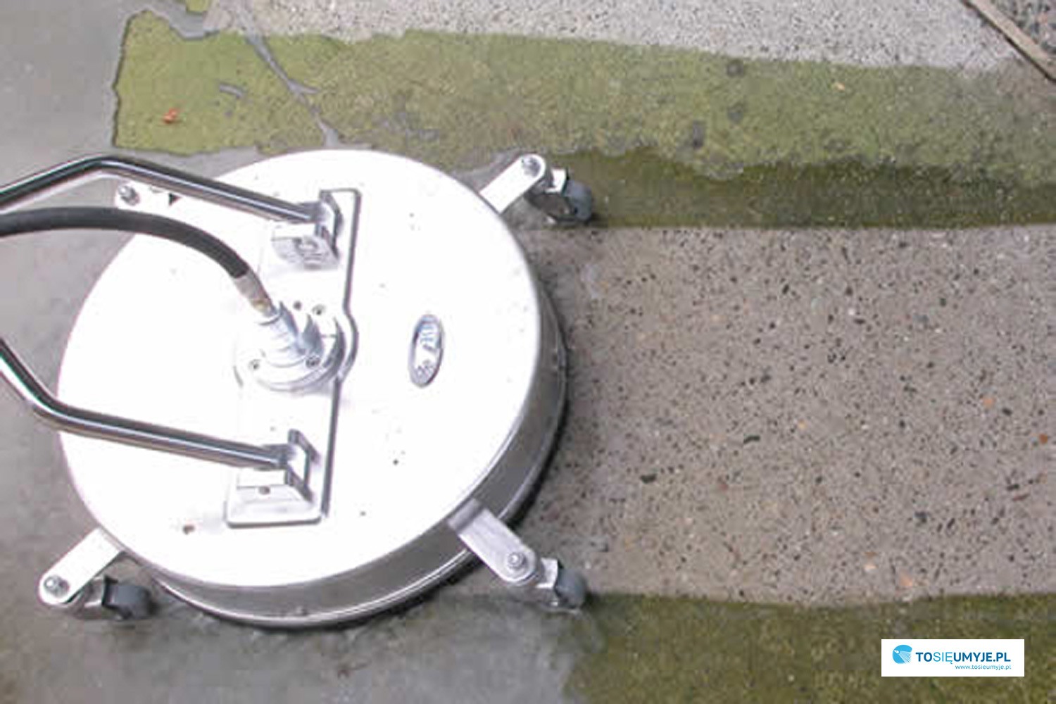 Okrągła, metalowa myjka ciśnieniowa z dyszami obrotowymi, czyszcząca fragment betonowej powierzchni z zielonego nalotu.