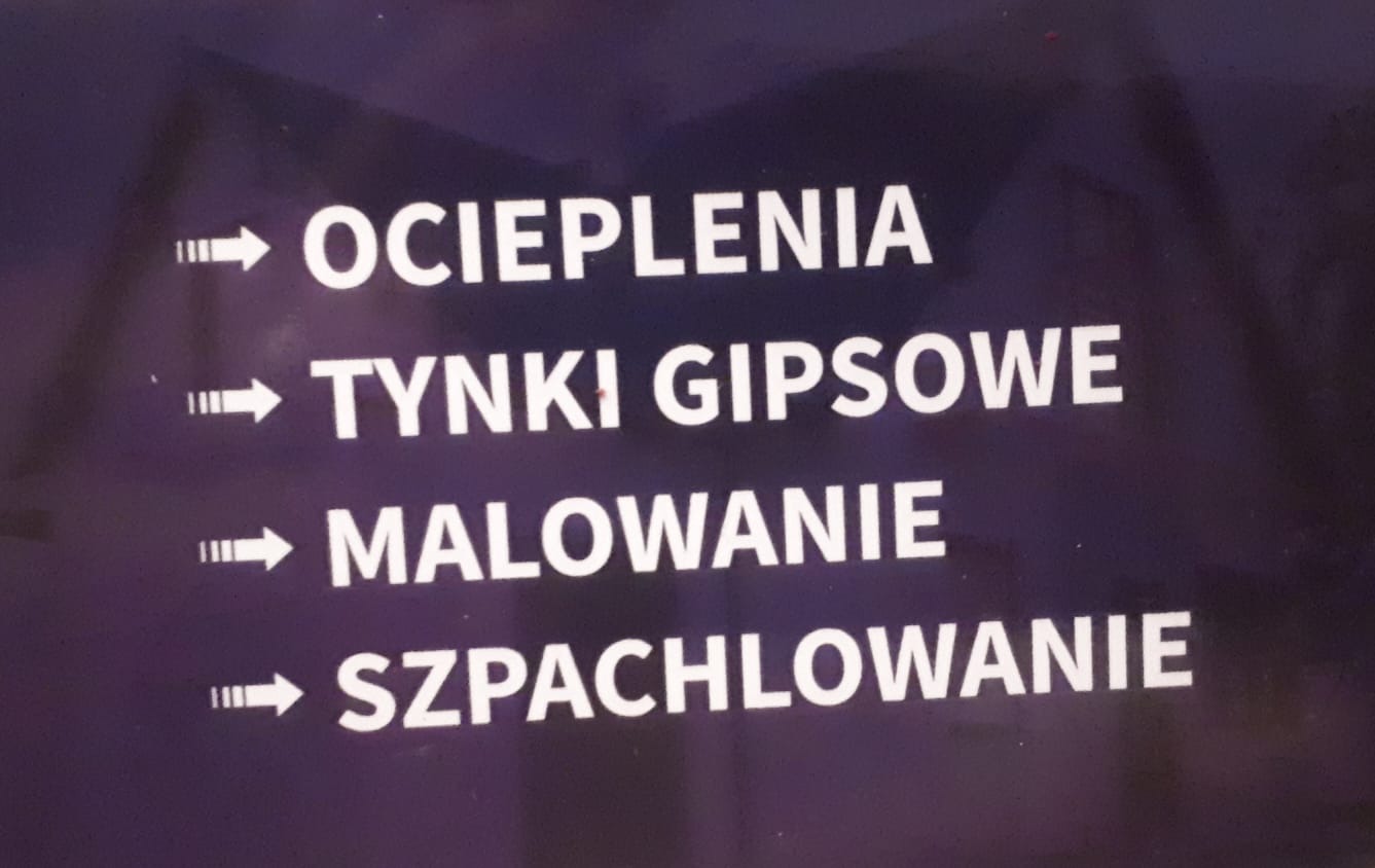 Tablica informacyjna z białymi napisami na ciemnym tle, wskazująca na usługi: Ocieplenia, Tynki Gipsowe, Malowanie, Szpachlowanie.