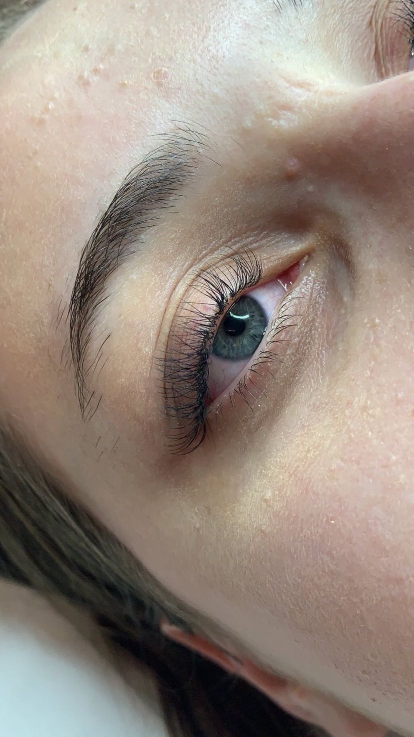 Zbliżenie na oko z przedłużonymi rzęsami, widoczne drobne niedoskonałości skóry na powiece i skroni.