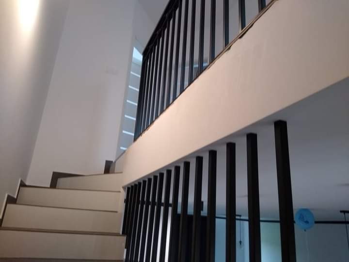 Schody wewnętrzne z balustradą z pionowych, czarnych prętów i drewnianą poręczą, widok z dołu na jasne, minimalistyczne wnętrze.