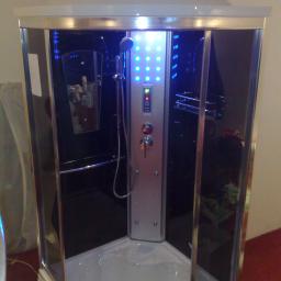 Rem-lux - Nowoczesna kabina prysznicowa z hydromasażem, podświetlana niebieskimi diodami, widoczne panele sterowania i dysze, lustro z kosmetykami w tle, chromowane wykończenia.