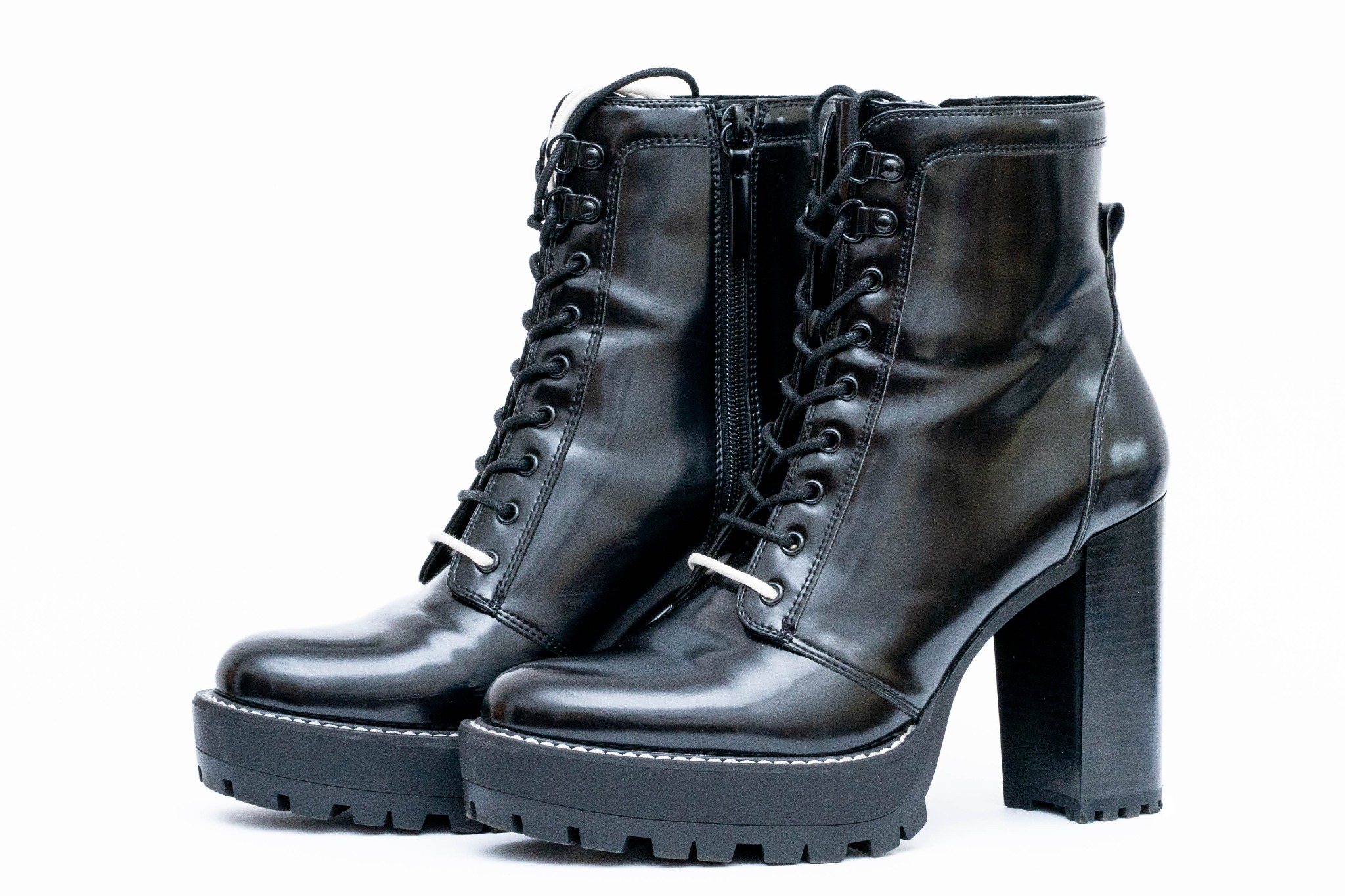 Para czarnych, lakierowanych botków na grubej platformie i wysokim, kwadratowym obcasie, sznurowane, z zamkiem błyskawicznym, na białym tle.