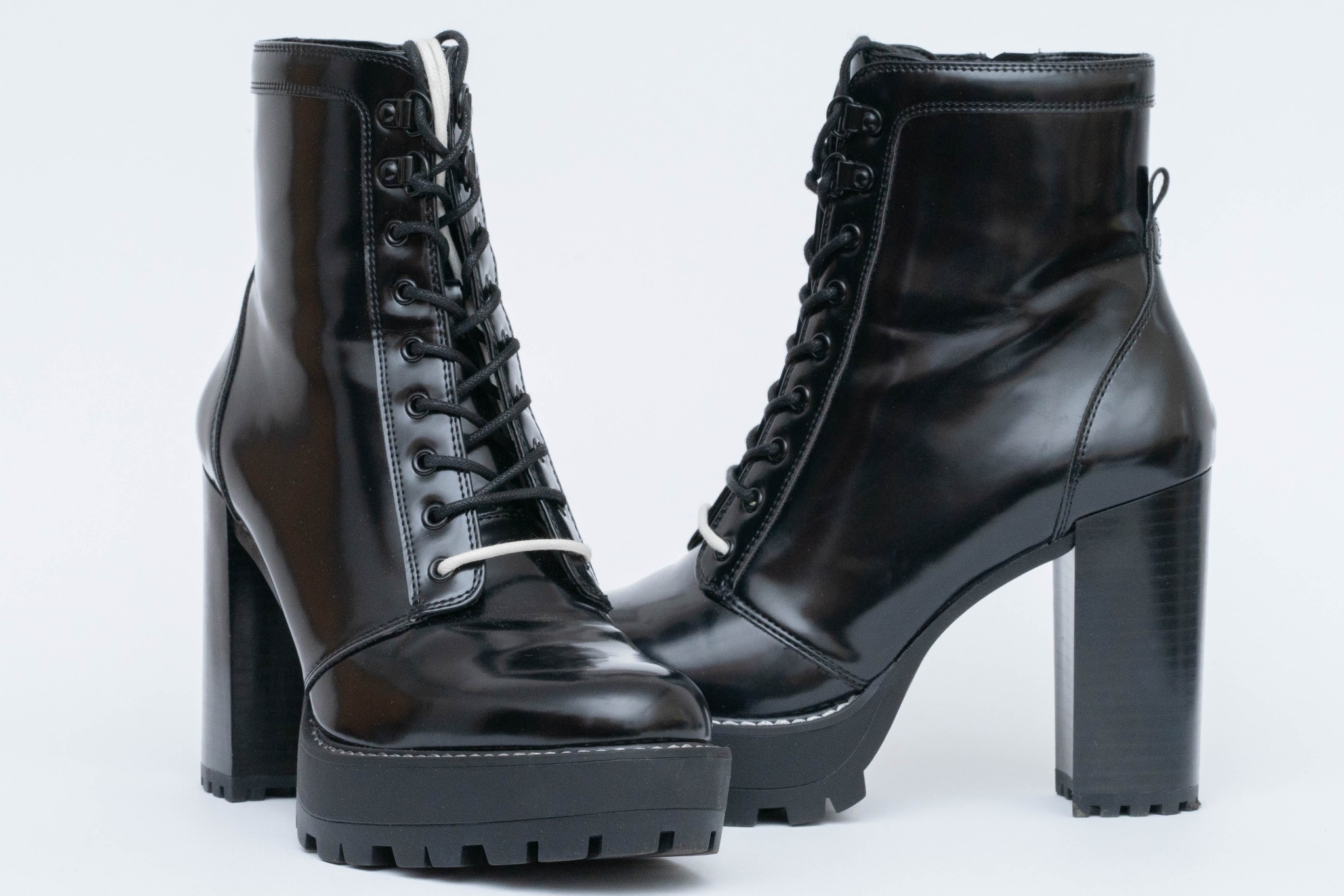 Para czarnych, lakierowanych botków sznurowanych na grubej platformie z wysokim, klockowym obcasem na białym tle.