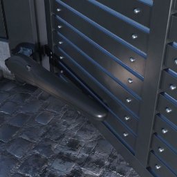 SPIDPOOL Paweł Łukaszyk - Szara, metalowa brama z automatycznym napędem, widoczny mechanizm siłownika na tle kostki brukowej i wbudowanego oświetlenia.