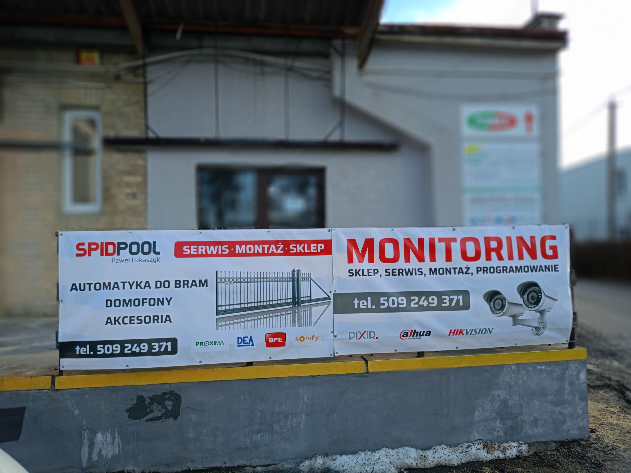 Baner reklamowy firmy Spidpool z ofertą automatyki do bram, domofonów i monitoringu. Widoczne logo firm Proxima, DEA, BFT, Somfy, Dixir, Alhua i Hikvision.