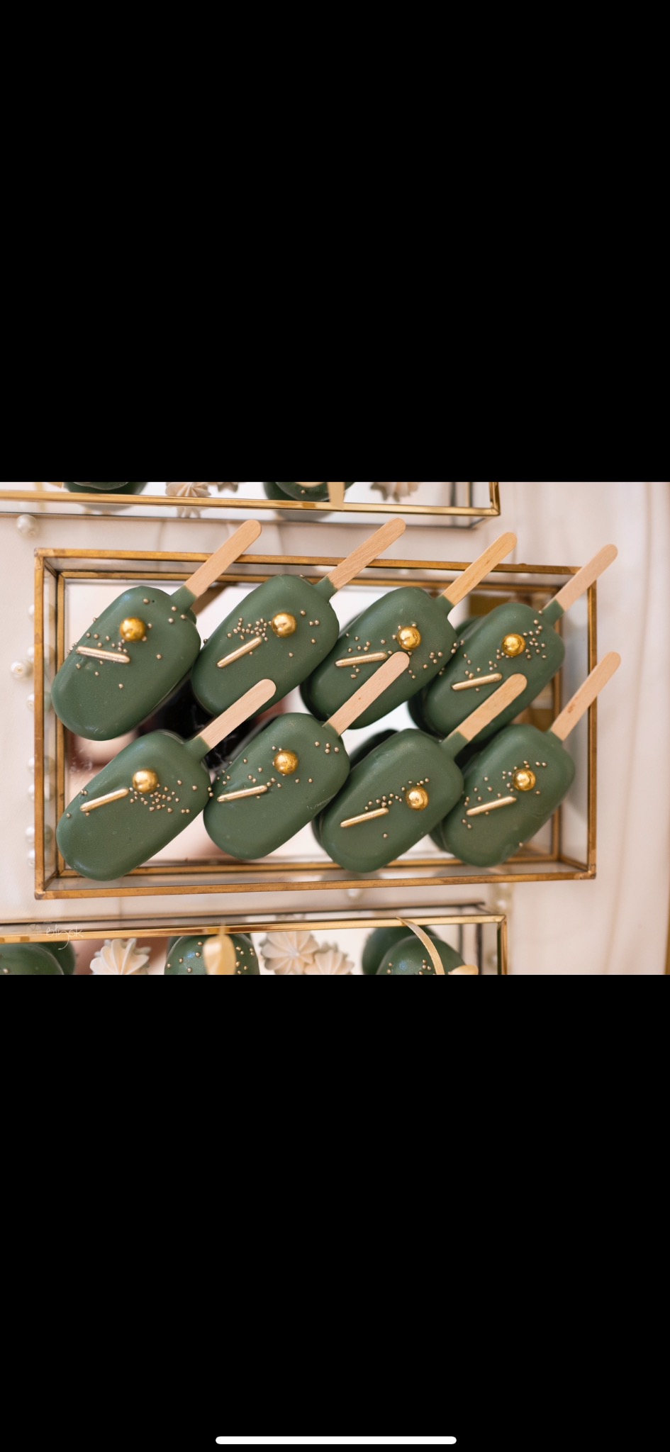 Dekoracyjne cake pops w odcieniach zieleni, zdobione złotymi elementami, ułożone na eleganckich, złotych paterach. Idealne na wyrafinowane przyjęcie.