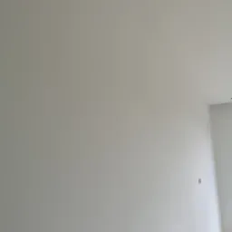 Wnętrze po nałożeniu jasnej, jednolitej warstwy wykończeniowej na ścianach i suficie, widoczne puszki elektryczne przygotowane do montażu.