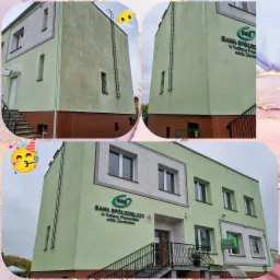 Budynek banku spółdzielczego SGB z jasnozieloną elewacją, widoczne ślady zacieków na ścianie, zamontowana drabina fasadowa, w tle pochmurne niebo.