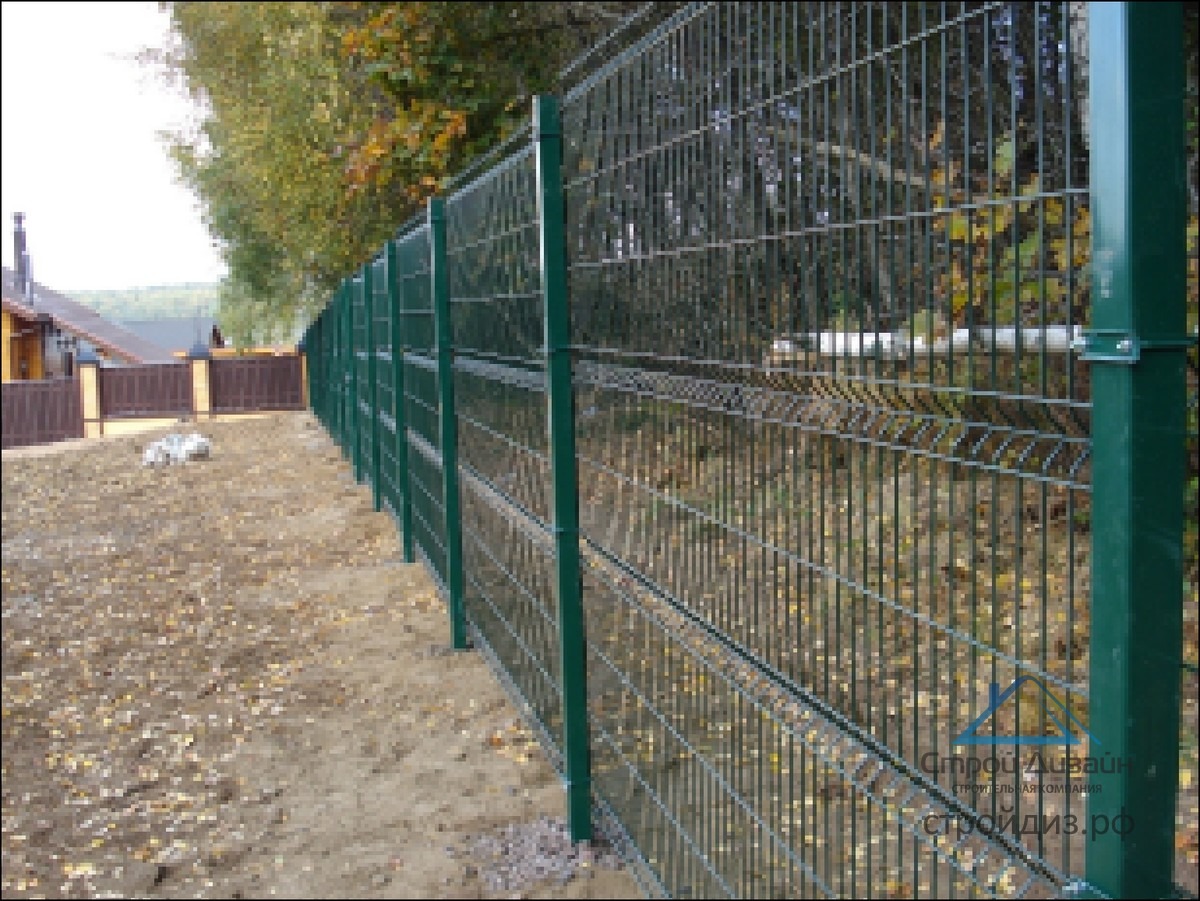 Nowoczesne, zielone ogrodzenie panelowe z widoczną konstrukcją stalową słupków w Szczecinie, zamontowane na nierównym terenie z widocznymi liśćmi i gruzem.