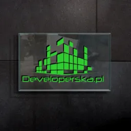 Szklana tabliczka z zielonym logo firmy Developerska.pl na ciemnej, teksturowanej ścianie.
