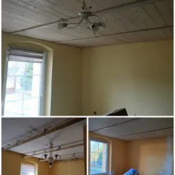 Pokój z żółtymi ścianami i drewnianym sufitem w trakcie malowania, widoczne zabezpieczenia mebli folią malarską i niedomalowane fragmenty ścian.