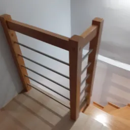 Fragment schodów z drewnianymi stopniami i balustradą z drewnianych słupków i metalowych prętów, widok z góry.