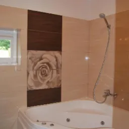 Nowoczesna łazienka z narożną wanną z hydromasażem, beżowe płytki z motywem kwiatowym, oświetlenie LED w kolorze czerwonym przy suficie.