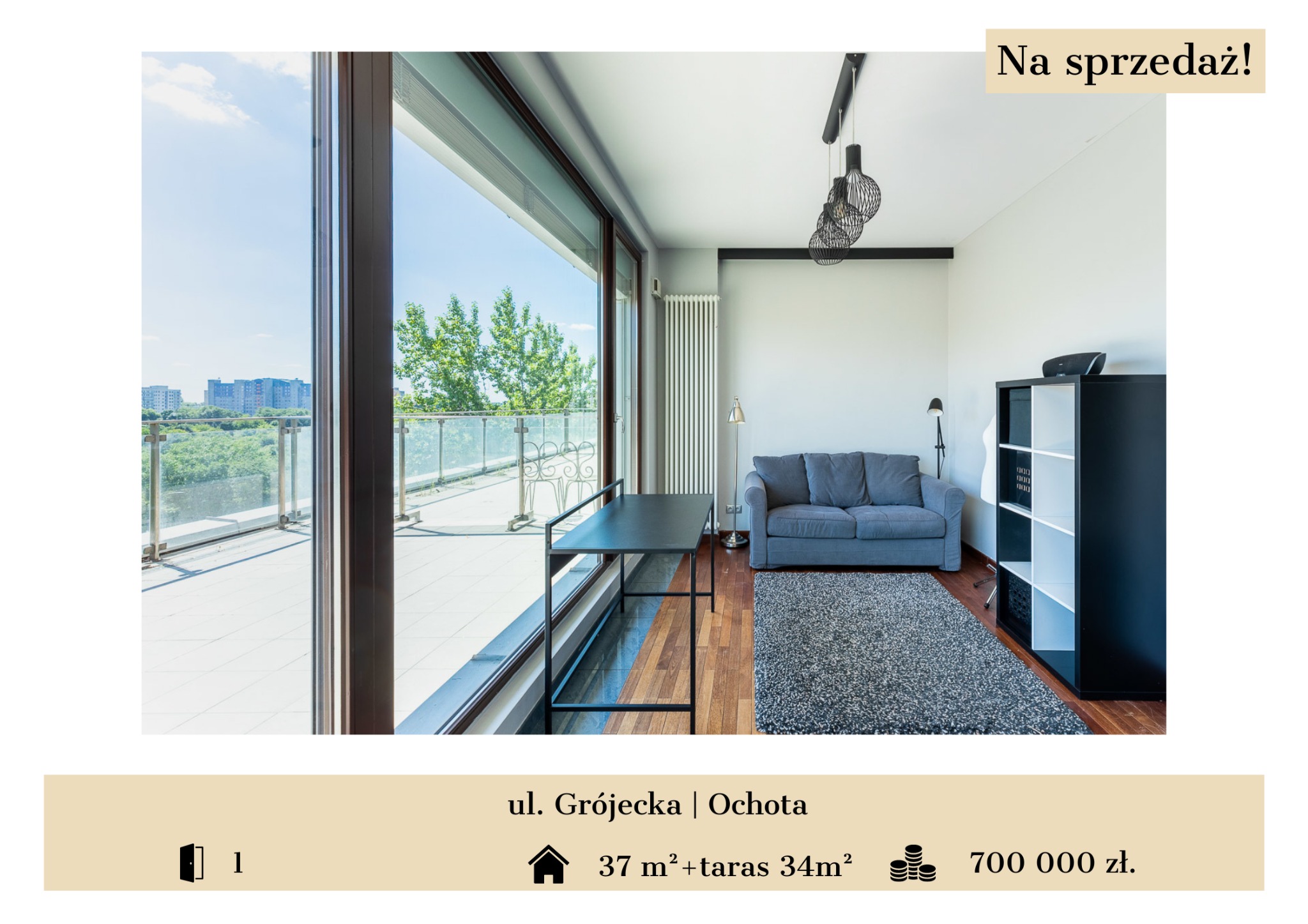 Jasne wnętrze mieszkania z dużym oknem balkonowym, widok na zieleń i zabudowę miejską, szara sofa, czarny regał i lampa wisząca z metalowych drutów.