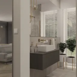 Nowoczesna łazienka z minimalistyczną umywalką nablatową, szarą szafką z ryflowanym frontem i złotą armaturą, uzupełniona roślinami w białych donicach na złotych nóżkach.