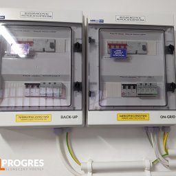 SolProgres - Dwie rozdzielnice PV AC, jedna oznaczona jako 'BACK-UP', druga 'ON-GRID', z widocznymi elementami instalacji elektrycznej i przewodami. Żółta naklejka ostrzegawcza informuje o niebezpieczeństwie...