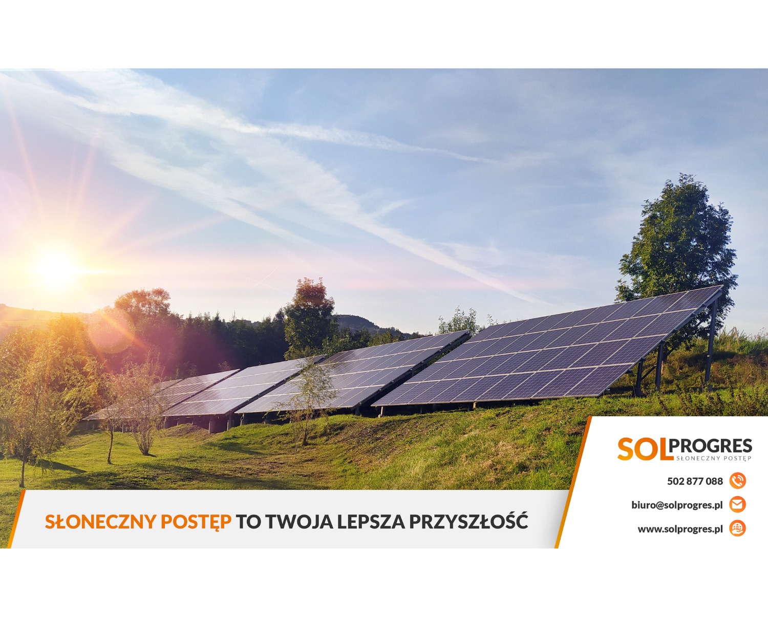 Instalacja paneli słonecznych na zielonym wzgórzu, widok z dołu pod kątem, w tle drzewa i zachodzące słońce.