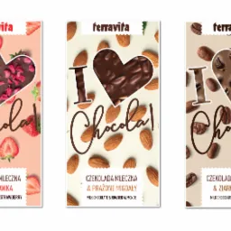 Trzy różne opakowania czekolady mlecznej Terravita: z truskawkami, prażonymi migdałami i ziarnami kawy, każde z napisem 'I Chocolat!' i motywem serca wypełnionego odpowiednim składnikiem.