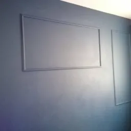 Granatowa ściana z dekoracyjnymi listwami tworzącymi prostokątne panele.