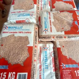 PRODUCENT PELLETU MAXHANDEL - Stos worków 15 kg z pelletem drzewnym marki MAXPELLET, widoczne certyfikaty jakości i informacja o produkcji z trocin drewna iglastego.