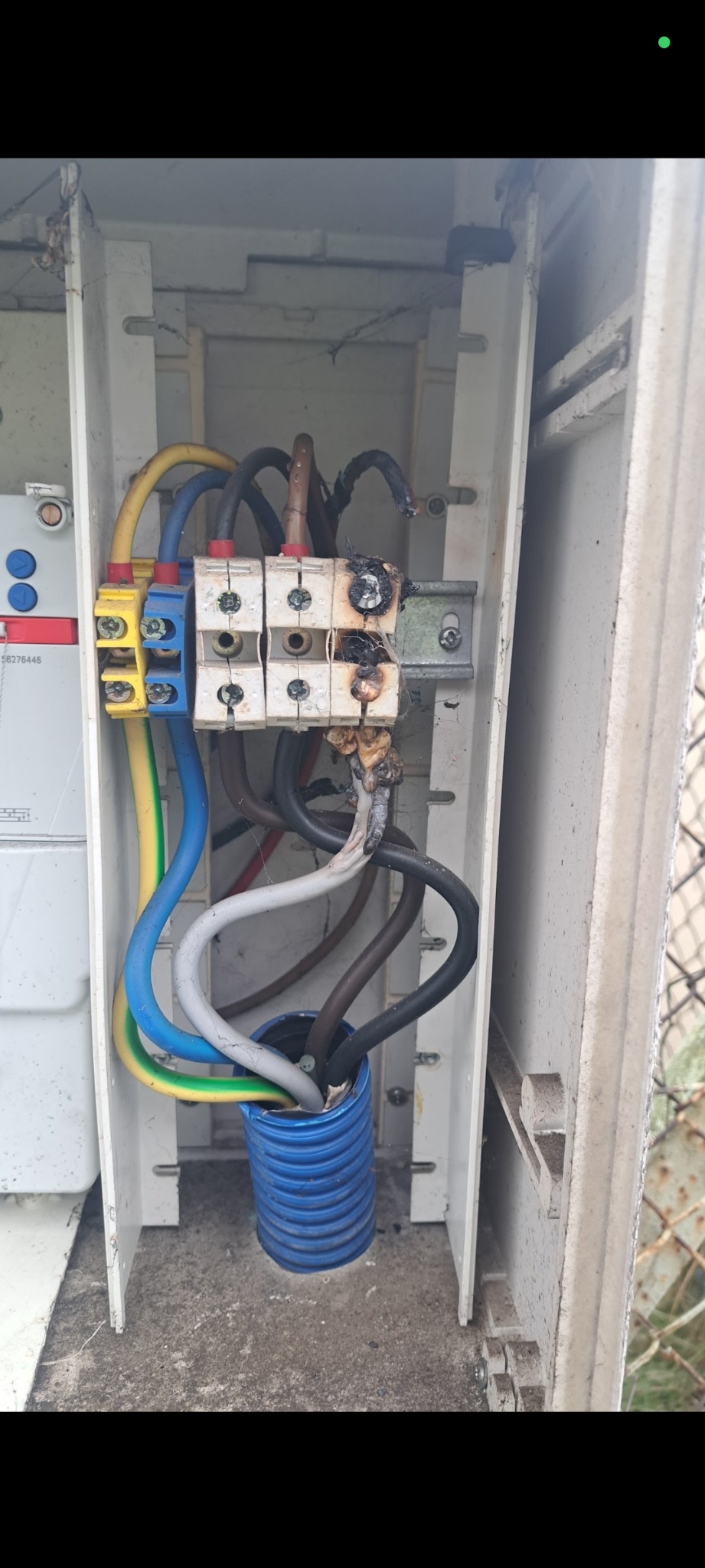 Spalona instalacja elektryczna w skrzynce. Widoczne uszkodzone kable i osmolone elementy. Awaria elektryczna, niebezpieczeństwo pożaru.