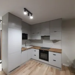 Nowoczesna kuchnia w odcieniach szarości z drewnianym blatem i oświetleniem punktowym, widok na całe pomieszczenie z perspektywy podłogi