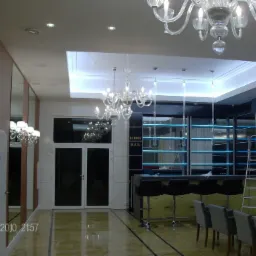 Kryształowe żyrandole i oświetlenie LED w lobby baru we Wrocławiu, widoczne z poziomu podłogi z połyskiem.